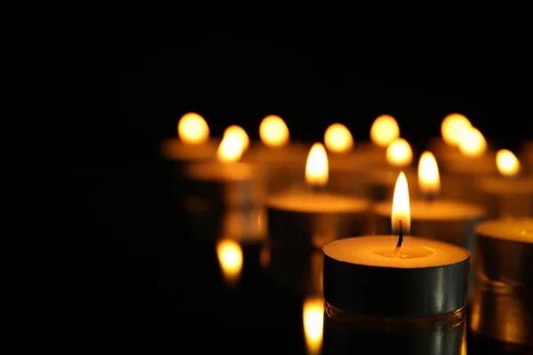 Grupa palących się świec na czarnym tle, zbliżenie — Zdjęcie stockowe