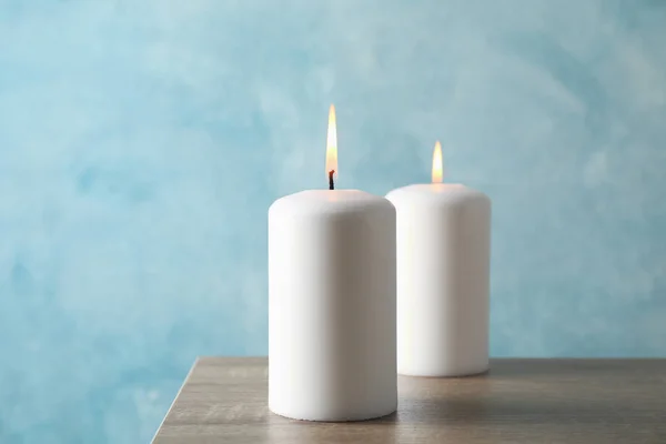 在蓝色背景的灰色桌子上燃着两支蜡烛，非常接近 — 图库照片