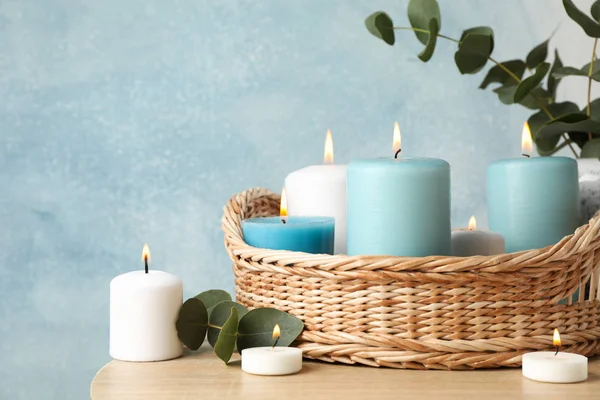 Burning candles, basket and vase with eucalyptus against blue ba — Stock Photo, Image