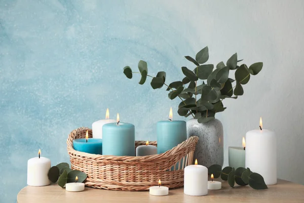 Горящие свечи, корзина и ваза с эвкалиптом против голубой ба — стоковое фото