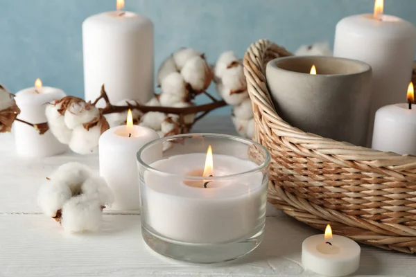 Burning candles, basket and cotton on white wooden table, close — Stock Photo, Image