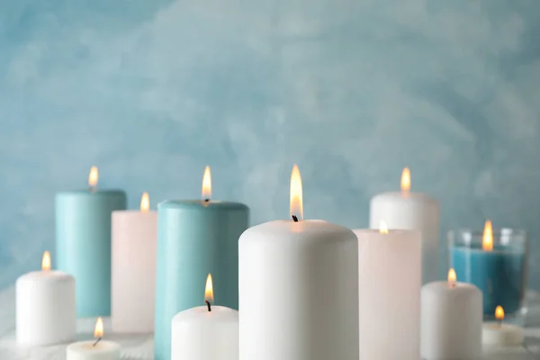 Diferentes velas acesas contra fundo azul, espaço para tex — Fotografia de Stock