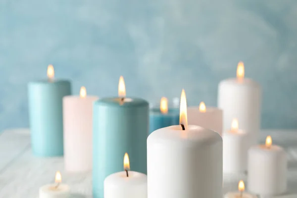 Different burning candles against blue background, space for tex — Stock Photo, Image