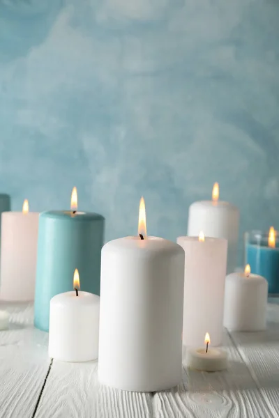 Different burning candles against blue background, space for tex — Stock Photo, Image