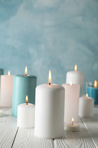 Diferentes velas acesas contra fundo azul, espaço para tex — Fotografia de Stock