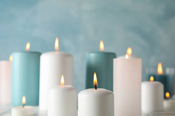 Diferentes velas acesas contra fundo azul, espaço para tex — Fotografia de Stock