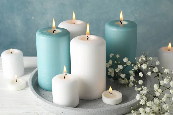 Горящие свечи, поднос и цветок на синем фоне, закрыть — стоковое фото
