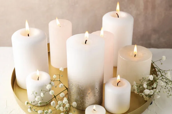 Płonące świece, taca i kwiat na białym stole, zbliżenie — Zdjęcie stockowe