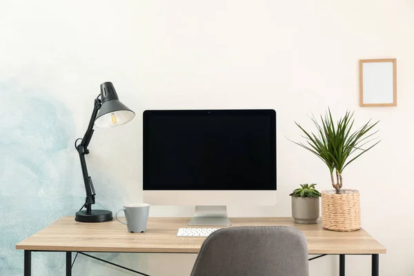Lugar de trabajo con ordenador y planta sobre mesa de madera. Azul claro y — Foto de Stock