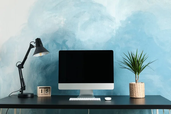 Робоче місце з комп'ютером і рослиною на дерев'яному столі. Блакитний і білий — стокове фото