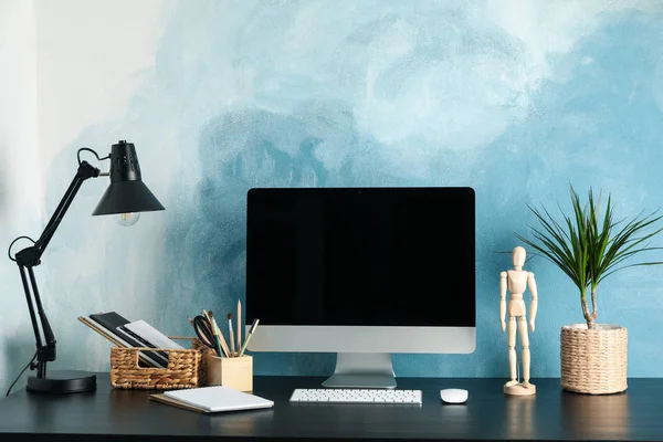 Workplace with computer and plant on wooden table. Blue and whit — Stock Photo, Image