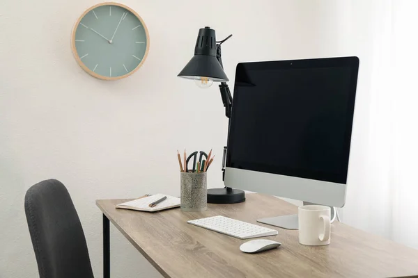 Робоче місце з комп'ютером, чашкою і лампою на дерев'яному столі. Білий бек — стокове фото