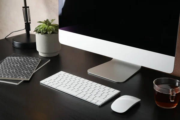 Milieu de travail avec ordinateur, tasse de thé et plante sur ta en bois noir — Photo