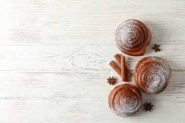 Beyaz üzerine pudra şekerli tarçın ruloları ve tarçın çubukları. 