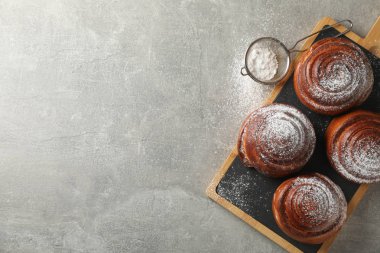 Gri arkaplanda pudra şekerli tarçınlı rulo.