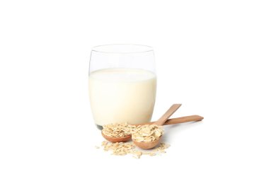 Beyaz arka planda yulaf sütü ve kaşıkta yulaf ezmesi.