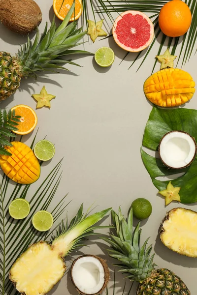 Composición con frutas exóticas y hojas de palma sobre fondo gris —  Fotos de Stock