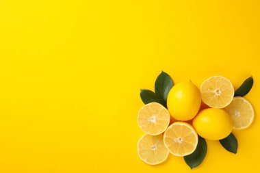 Sarı arka planda sulu limonlar ve yapraklar, üst manzara