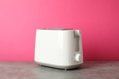 Pembe arkaplana karşı gri masadaki tost makinesi, metin için boşluk