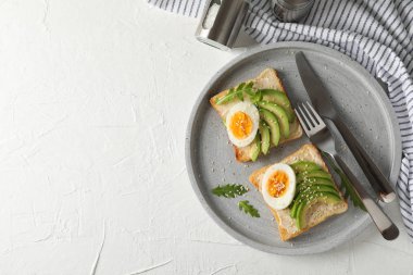 Avokado, yumurta, çatal bıçak ve havluyla kızarmış ekmek.