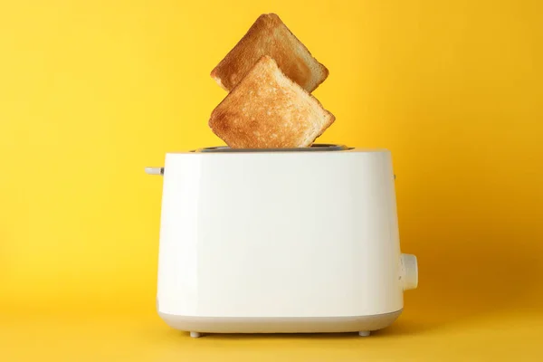 Torradeira com fatias de pão no fundo amarelo, espaço para texto — Fotografia de Stock