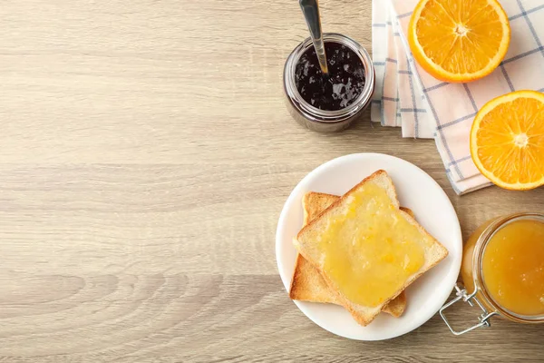 Toast op bord, jam, handdoek en sinaasappel op houten ondergrond, bovenkant — Stockfoto