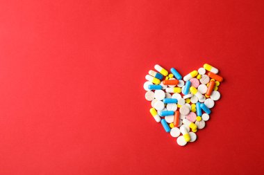 Kırmızı arka planda haplardan yapılmış kalp, mesaj için boşluk. Üst görünüm