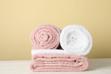 Beyaz ahşap masa üzerindeki katlanmış havlular, bej arka plan, sp