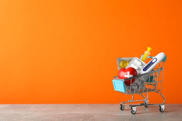 Mini carrello della spesa con forniture mediche su sfondo arancione, s — Foto Stock