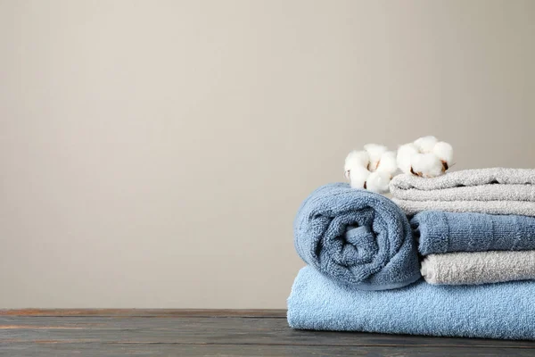 Vikta handdukar och bomull på träbord mot grå bakgrund — Stockfoto