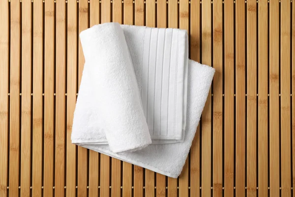 Белые свежие полотенца на бамбуковом фоне, вид сверху — стоковое фото