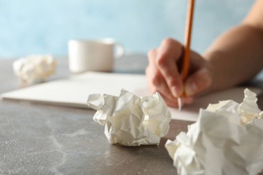 Gri masaya kağıt toplar ve bir fincan kahve yazan kişi., 