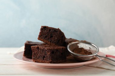 Çikolatalı pasta dilimleri ve ahşap masa üzerinde süzgeç.