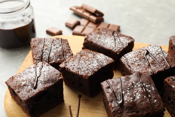 Board with chocolate cake slices and chocolate on grey backgroun