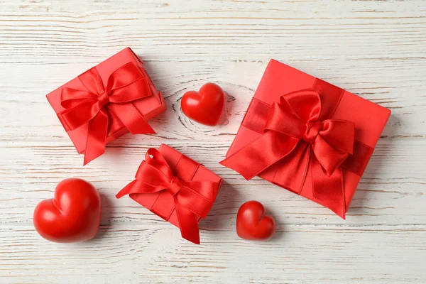 Geschenkschachteln mit Schleife und Herzen auf Holzgrund, Ansicht von oben — Stockfoto