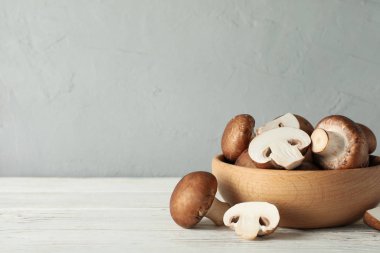 Beyaz ahşap arka planda kasede taze şampiyon mantarları, spa