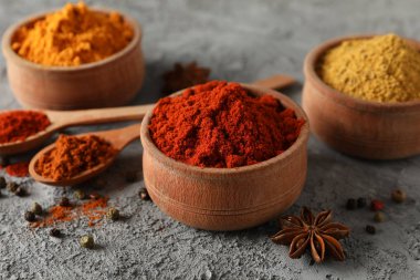 Gri arka planda farklı baharatlarla kaşıklar ve kaseler, kapat