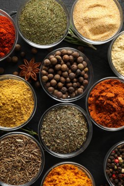 Siyah arka planda farklı baharat ve malzeme içeren kaseler.,