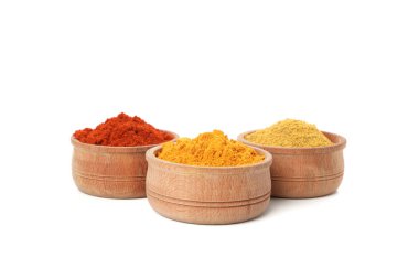 Kırmızı biber, köri ve zerdeçal tozuyla izole edilmiş ahşap kaseler.