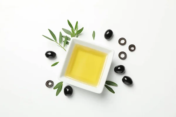 Cuenco cuadrado con aceite de oliva, aceitunas y hojas sobre fondo blanco — Foto de Stock
