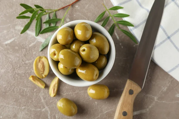 Skål med oliver, blad, kniv och handduk på grå bakgrund, till — Stockfoto