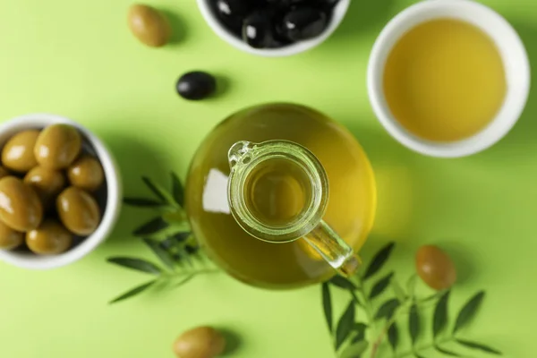 Olivy, láhev a miska s olivovým olejem na zeleném pozadí, horní — Stock fotografie