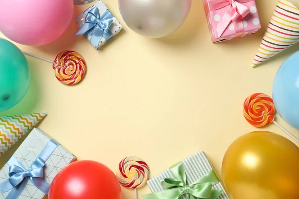 Luftballons, Geschenkboxen, Lutscher und Geburtstagsmützen auf farbigem Hintergrund — Stockfoto