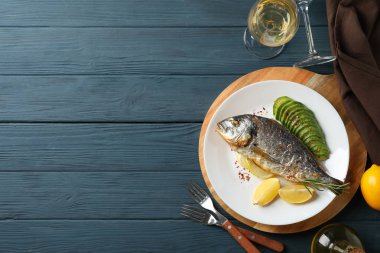 Süslü ahşap arka planda fırında Dorado balığı tabağı.