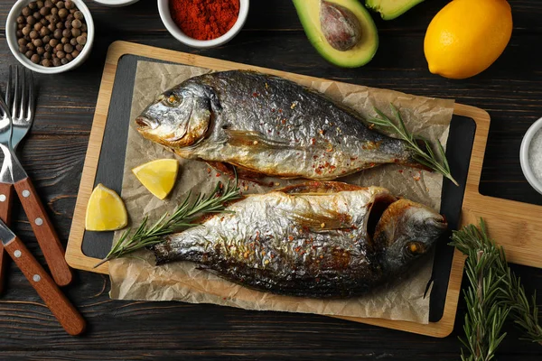 Cutting board with fried Dorado fishes and spice ingredients on — 스톡 사진