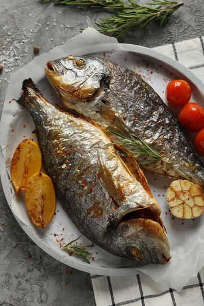 Plate with baked Dorado on garnished grey background, close up — 스톡 사진