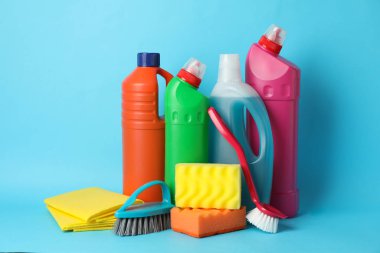 Deterjanlı şişeler ve mavi arka planda temizlik malzemeleri.,