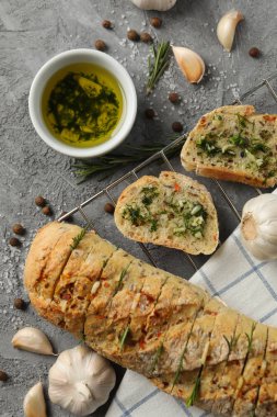 Gri arka planda lezzetli sarımsaklı ekmek ve baharatlar.