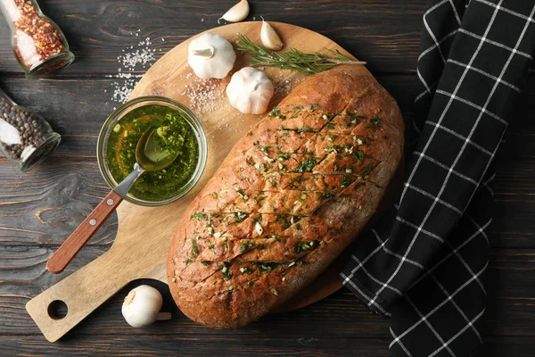 Board with garlic bread and spices on wooden background, top vie — Stock Photo, Image