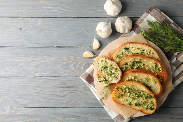 Plate with toasted garlic bread and dill on wooden background, t